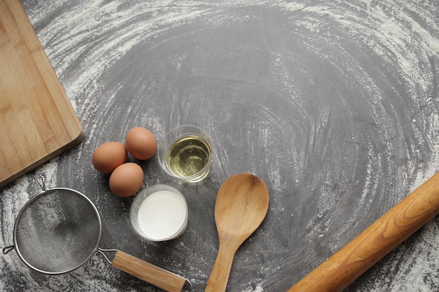 Chicken egg flour olive oil milk kitchen tool on gray table background