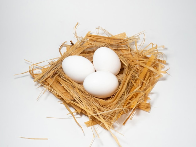 A chicken egg lies in the straw Three eggs