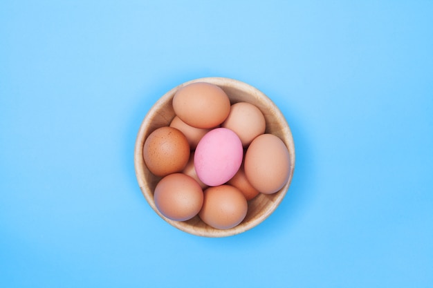 Chicken egg in wood bowl on blue background with preserved egg and space for copy .