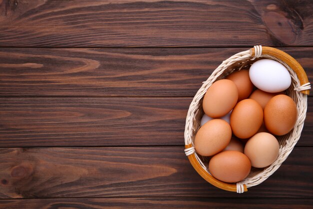 Chicken eggs in basket on brown wooden