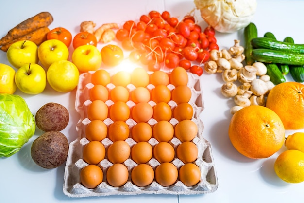 Chicken eggs in carton box on table Blurred fresh fruits and vegetables on background Rustic food concept