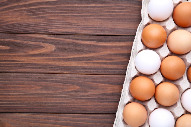 Chicken eggs in containers on brown wooden background