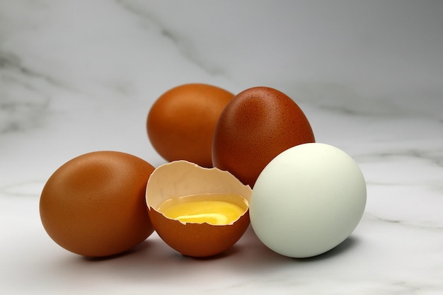 Chicken eggs of different colors and one broken with the yolk inside