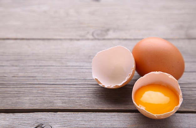 Chicken eggs and half with yolk on a grey background.