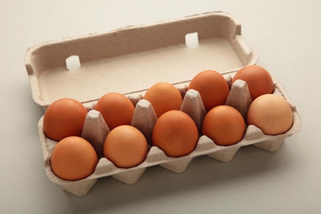 Chicken eggs in an open egg carton on grey Top view with copy space Natural healthy food and organic farming concept