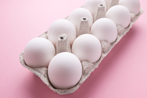 Chicken eggs in a tray close-up on a pink background.