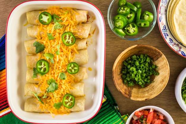 Chicken enchiladas with cheddar cheese and sauce.