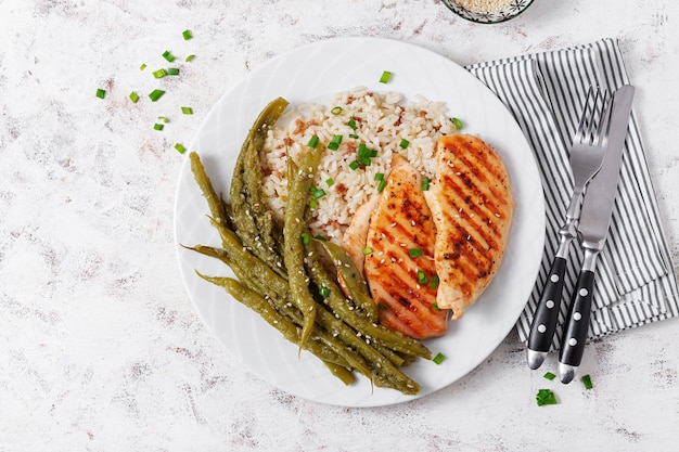 Chicken fillet cooked on a grill and garnish of rice green beans Top view