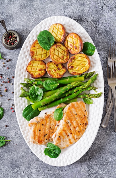 Chicken fillet cooked on a grill with a garnish of asparagus and baked potatoes. Dietary menu. Healthy food. Flat lay. Top view