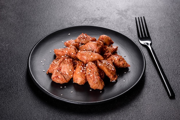 Chicken fillet in sesame seeds, teriyaki sauce on a black stone plate. Asian cuisine