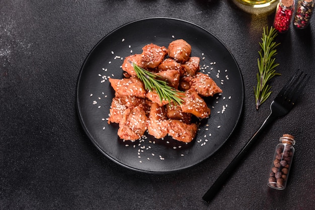 Chicken fillet in sesame seeds, teriyaki sauce on a black stone plate. Asian cuisine