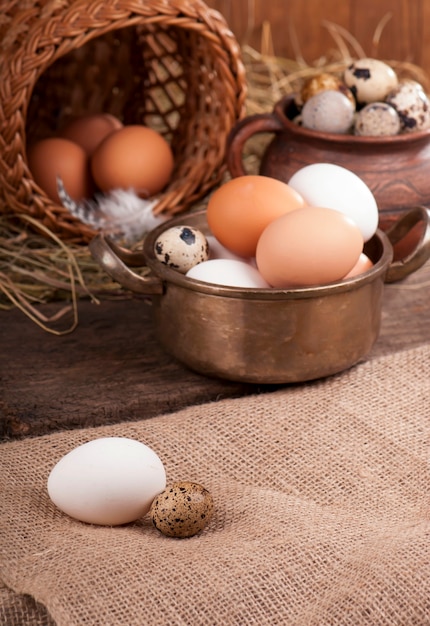 Chicken fnd quail eggsin basket on wooden surface