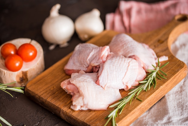 Chicken for grilled, spices, herbs, tomatoes, mushrooms on dark background, top view. Raw meat chicken for cooking. Delicious balanced food concept