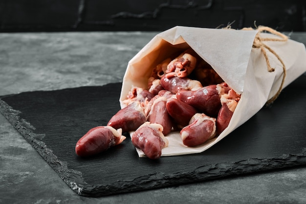 Chicken hearts on a dark stony background. Chicken giblets.