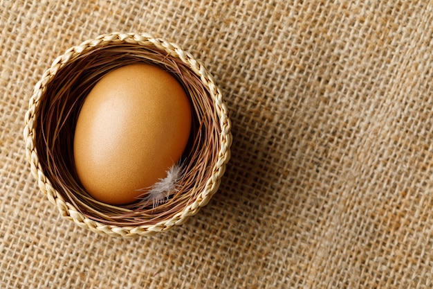 Chicken or hen egg in wicker basket on sackcloth