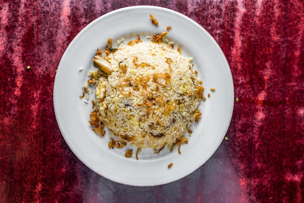 Photo chicken kacchi biryani or biriyani rice with fried onion served in plate isolated on table background top view of bangladeshi indian and pakistani food