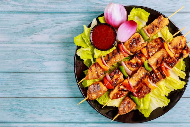 Photo chicken kebab on wooden skewer with salad and sauce