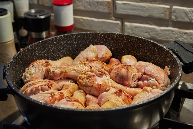 Chicken legs fried in pan on gas stove