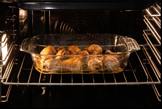 Chicken legs in a glass tray are baked in the oven