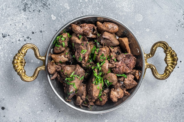 Chicken liver stew with onions and parsley in a skillet Gray background Top view