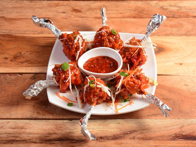 Chicken lollipop schezwan is an Indian Chinese appetizer served over a wooden rustic background