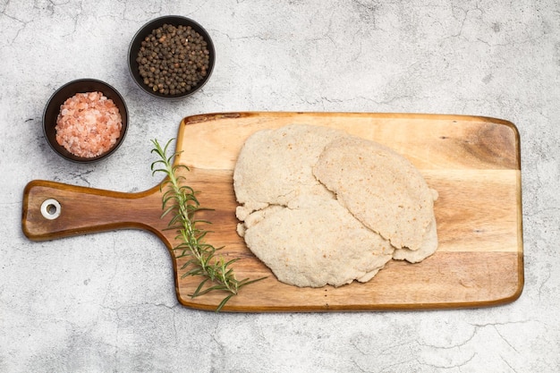 Chicken milanese on a wooden kitchen board on a stone background in a top view