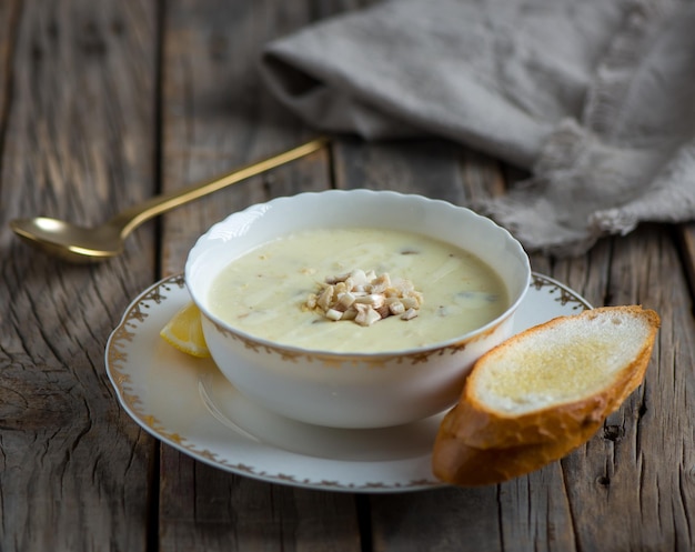 Chicken mushroom soup with garlic bread served in a bowl isolated on wooden background side view