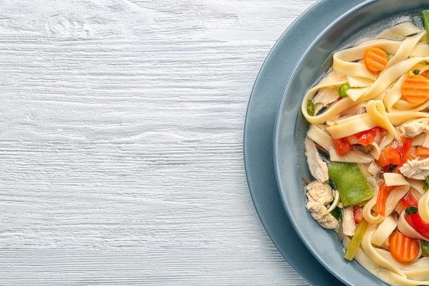 Chicken noodle soup in plate on wooden background