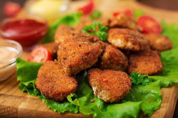 Chicken nuggets and sauce on a wooden table.