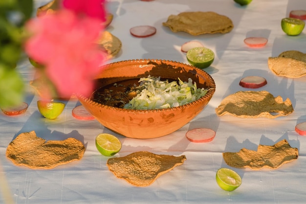 Chicken pozole accompanied by oregano lettuce onion radish lemon chili and toast