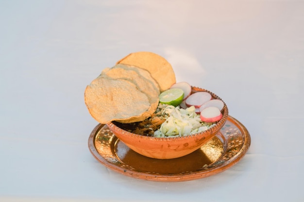 Chicken pozole accompanied by oregano lettuce onion radish lemon chili and toast