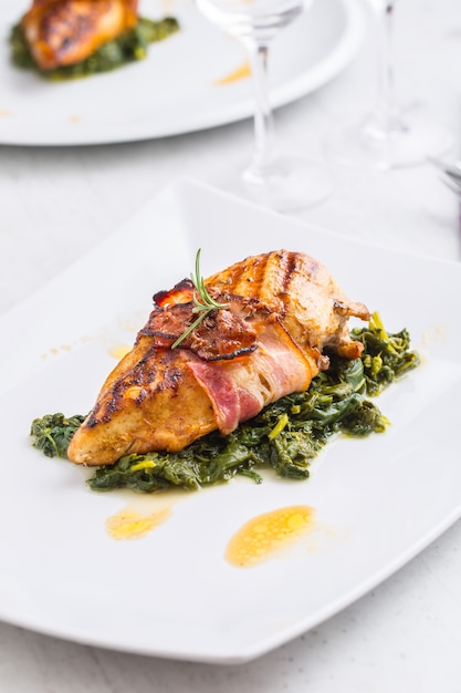 Chicken roasted breast with bacon and spinach on white plate Culinary food  in pub or restaurant