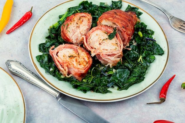 Chicken roll and fried spinach on plate