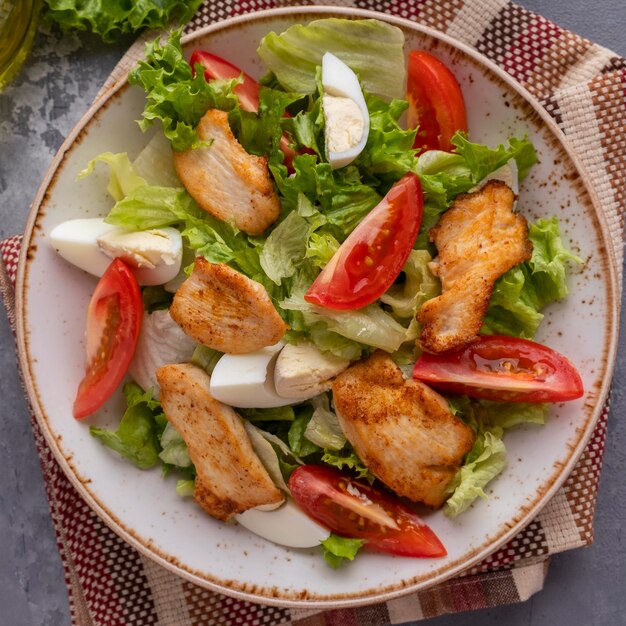 Chicken salad with fresh vegetables on a plate Healthy and diet food concept Top view Closeup