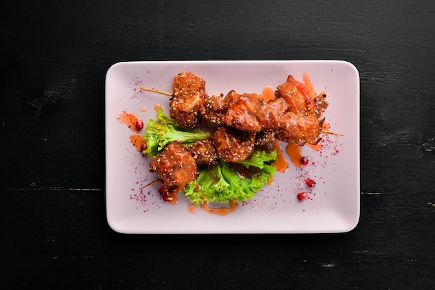 Chicken shish kebab with sesame seeds and barbecue sauce On a wooden background Top view Free space for your text