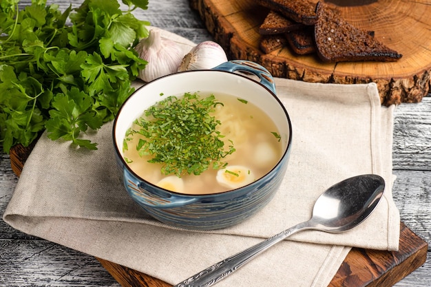 Chicken soup soup with chicken and herbs on a wooden white background