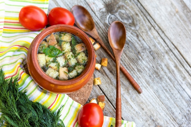 Chicken soup with croutons on a wooden background with herbs and various seasonings.