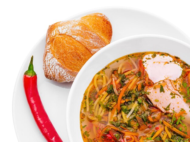 Chicken soup with noodles and vegetables in white bowl