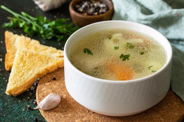 Chicken soup with vegetables on a dark stone table top