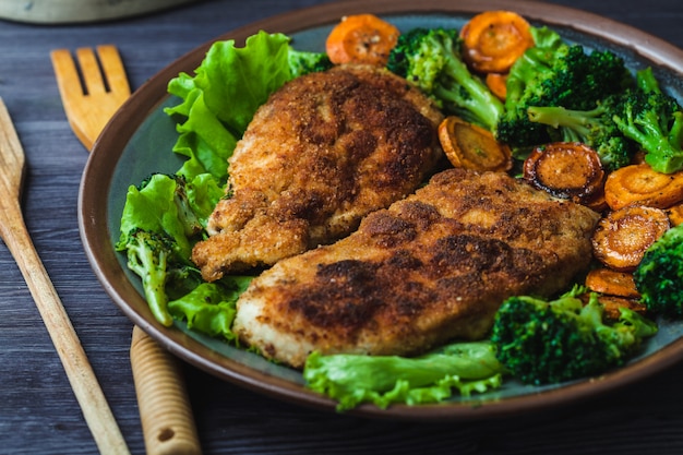 Chicken steak in breadcrumbs with vegetables on a plate