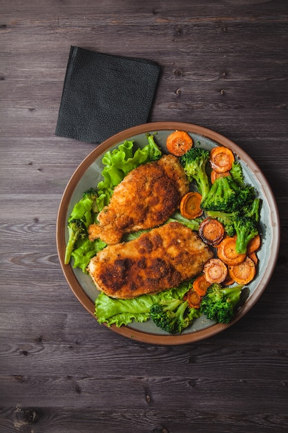 Chicken steak in breadcrumbs with vegetables on a plate