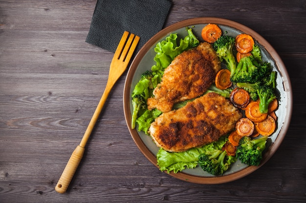 Chicken steak in breadcrumbs with vegetables on a plate