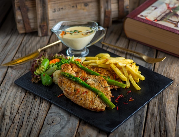 Chicken steak with fries isolated on cutting board on wooden background side view of steak