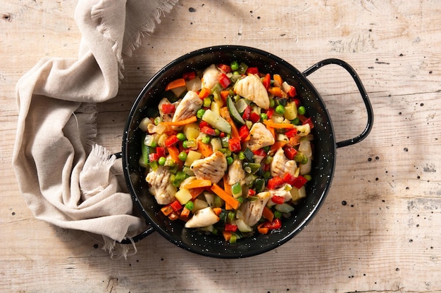 Photo chicken stir fry and vegetables on wooden table