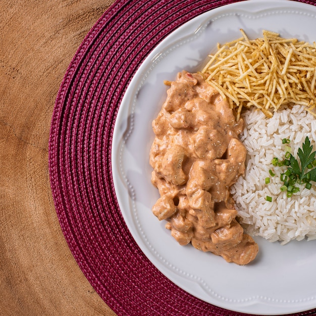 Chicken stroganoff accompanied with rice, salad and potato straw.