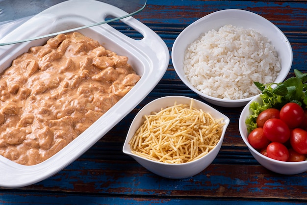 Chicken stroganoff accompanied with rice, salad and potato straw.