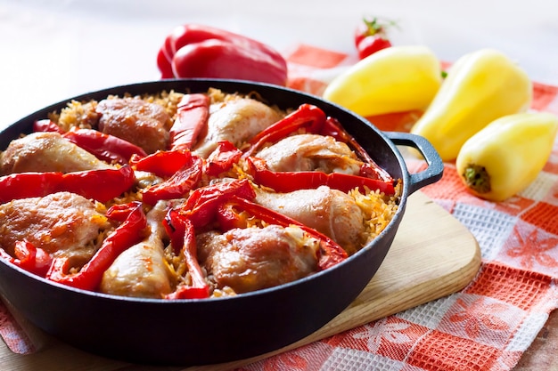 Chicken thighs and legs baked over a bed of rice and red bell pepper in cast iron stewpan