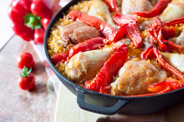 Chicken thighs and legs baked over a bed of rice and red bell pepper in cast iron stewpan