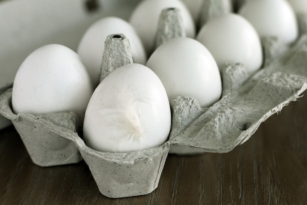 Chicken white eggs in a carton package on a wooden table