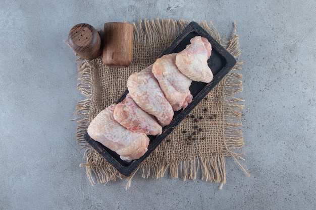 Chicken wings on a board on a burlap napkin, on the marble surface.